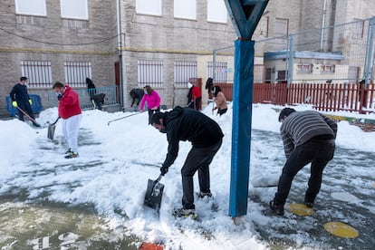 Grupo de padres voluntarios recogiendo nieve en el CEIP Victor Pradera de Leganés.