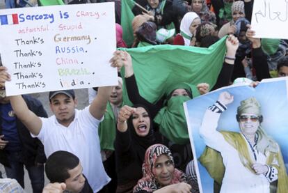 Un partidario de Gadafi, con un cartel en el que insulta al presidente Sarkozy y agradece a los países que se abstuvieron en la ONU.
