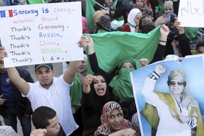 Un partidario de Gadafi, con un cartel en el que insulta al presidente Sarkozy y agradece a los países que se abstuvieron en la ONU.