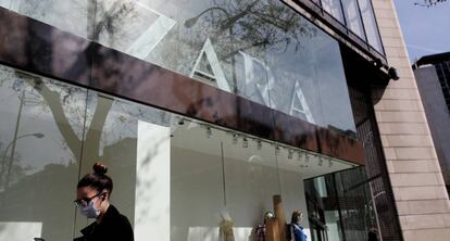 Una mujer con mascarilla pasa junto al escaparate de la tienda Zara en Madrid.