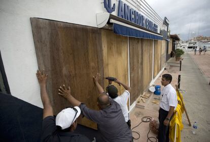 Un grupo de trabajadores protegen el escaparate de una tienda en Cabo San Lucas, Mexico, el 5 de septiembre.