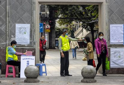 Un hombre mide la temperatura corporal de los visitantes a un recinto en Guangzhou (China).
