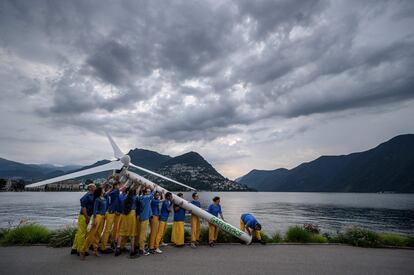 Un grupo de activistas de Greenpeace levanta, el lunes, un falso aerogenerador en el borde del lago Lugano, Suiza. La manifestación tiene por objetivo pedir una reconstrucción sostenible de Ucrania, al margen de una Conferencia de Recuperación de Ucrania, en Lugano.