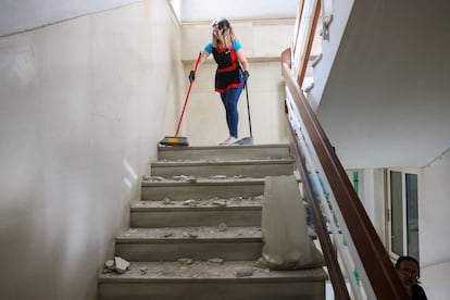 Una mujer limpia los escombros de las escaleras de un edificio, tras el terremoto que azotó la isla de Creta, en Heraclión (Grecia)