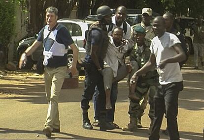 Personal militar de Mali traslada a un hombre herido a la salida del hotel de lujo Radisson Blu en Bamako (Mali).