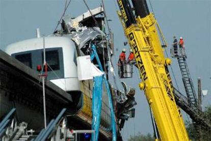 Dos bomberos tratan de rescatar el cuerpo de un viajero del tren siniestrado ayer en Lathen.