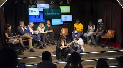 Ada Colau (detrás, en el centro) y miembros de otras candidaturas a las elecciones municipales debaten este martes con manteros en Barcelona.