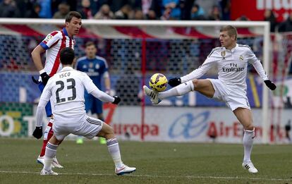 El centrocampista alemán del Real Madrid Toni Kroos (d) controla el balón ante su compañero 'Isco' Alarcón y el delantero croata del Atlético de Madrid Mario Mandzukic.