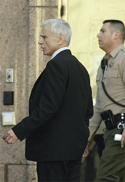 Robert Blake, custodiado por un policía durante un descanso en el juicio de Los Ángeles.