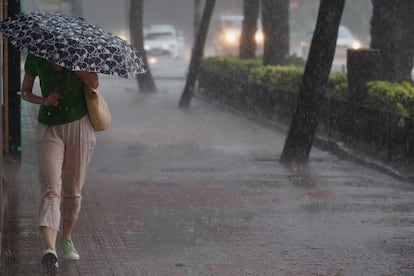 Una mujer camina por la acera bajo una intensa lluvia el sábado en Valencia.