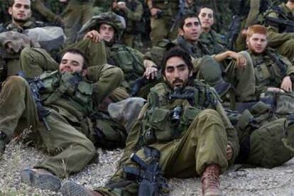 Un grupo de soldados israelíes descansa a la espera de un autobús el sábado cerca de la frontera entre Israel y Líbano.