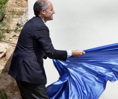 Camps retira la cortina que cubría un rótulo en una inauguración ayer en Cheste (Valencia).