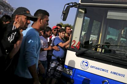 Refugiados y inmigrantes esperan para subir a un autobús después de su llegada a bordo del buque de pasajeros Tera Jet a el puerto de El Pireo