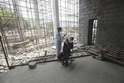 Un trabajador de la construcción reacciona mientras una sanitaria intenta obtener una muestra para detectar el coronavirus, en Nueva Delhi, India.