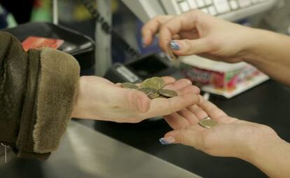 Una cajera ayuda a un cliente a contar las monedas de euro en un supermercado. 
