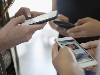 Un grupo de adolescentes usa sus teléfonos móviles.