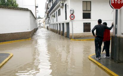 Dos jóvenes observan las calles de Écija inundadas por el agua.