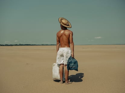 El manausense Cordeiro Freitas, cargado con comida, hace un alto en el camino de dos kilómetros que hay entre los barcos y la comunidad pesquera de Manacapuru.
