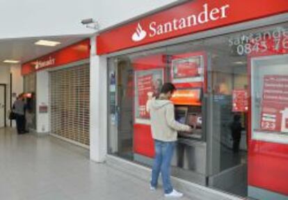 Un cliente retira dinero del cajero automático de la sucursal de Banco Santander donde un grupo de 'hackers' intentó perpetrar un robo.