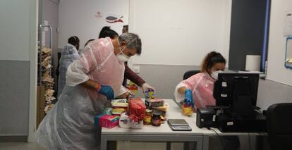 Voluntarios con guantes, mascarilla y traje de plástico registran alimentos para donaciones.