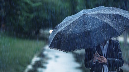 Una persona bajo un lluvia intensa con un paraguas antiviento.