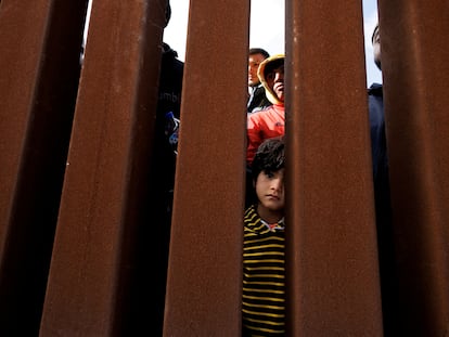 A young boy peers through the border wall as migrants gather between primary and secondary border fences in San Diego as the United States prepares to lift COVID-19-era restrictions known as Title 42, that have blocked migrants at the U.S.- Mexico border from seeking asylum since 2020, near San Diego, California, U.S., May 8, 2023. REUTERS/Mike Blake     TPX IMAGES OF THE DAY