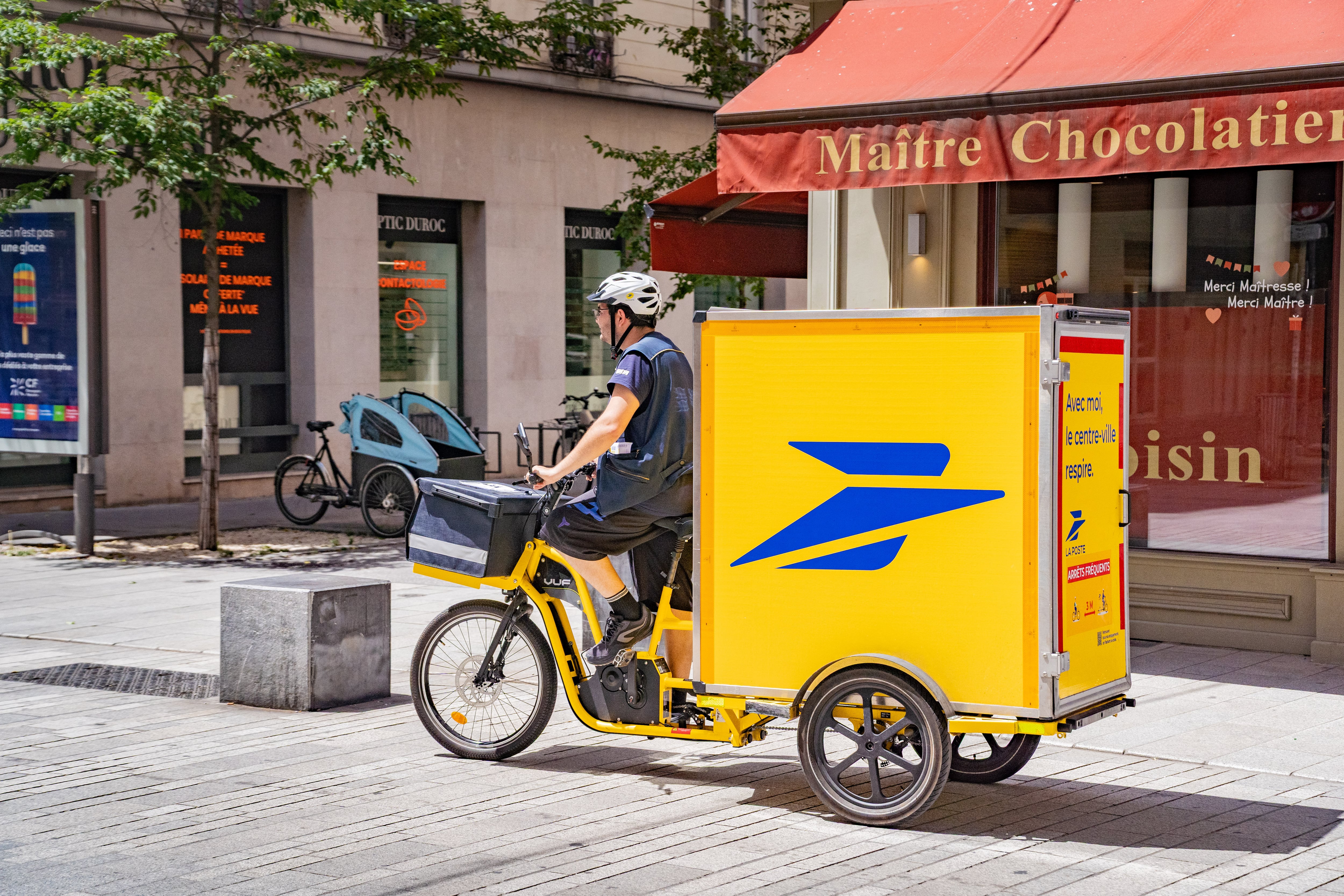 Un cartero de La Poste reparte correo en bicicleta por las calles de Lyon. 