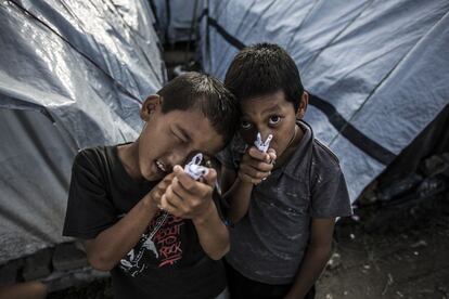 Niños del campamento de refugiados juegan con pistolas de papel.