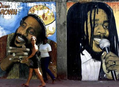 Dos mujeres ante un mural que representa a Denis Brown y Bob Marley, en Kingston (Jamaica)