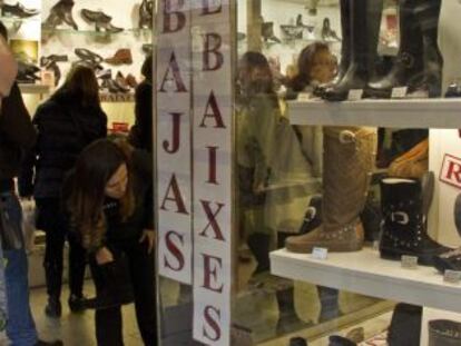 Un hombre mira los precios en el escaparate de una tienda. 