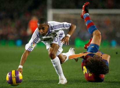 Puyol cae al césped mientras Robinho intenta proseguir la jugada.