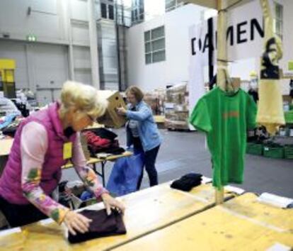 Dos voluntarias colocan la ropa donada por empresas y particulares.