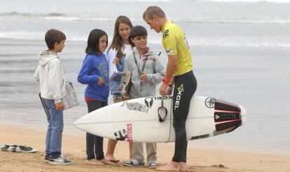 Cuatro niños piden un autógrafo a uno de los surfistas que participan en la prueba.