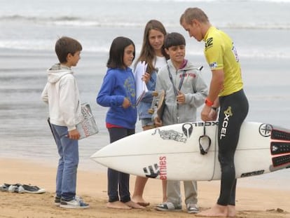 Cuatro niños piden un autógrafo a uno de los surfistas que participan en la prueba.
