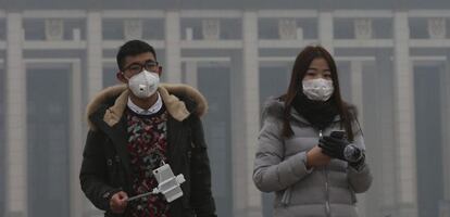 Una pareja usa mascarillas para protegerse de la contaminación ambiental durante una visita a la plaza de Tiananmen en Pekín (China).