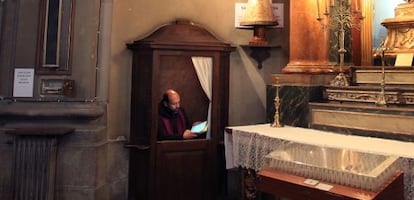 A priest uses his iPad in the church’s confessional, located next to one of the four TV screens that have been installed in the church.