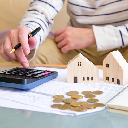 Selective focus at the wooden house with Asian men calculating his money for buy a new house or plan for home loan mortgage. Personal saving for home ownership.