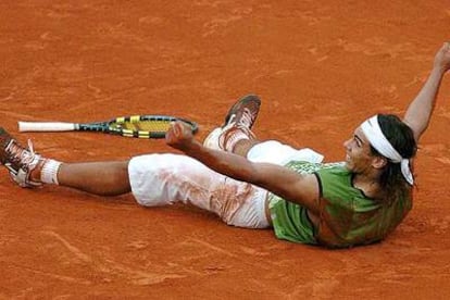Rafael Nadal, echado sobre la pista, puños cerrados, sonrisa abierta, tras el tanto decisivo.