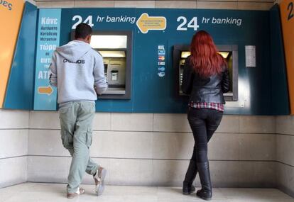 Dos personas retiran dinero de un cajero el sábado.