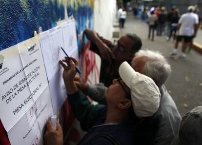 Un grupo de electores buscan en las listas dónde les toca votar en Caracas.