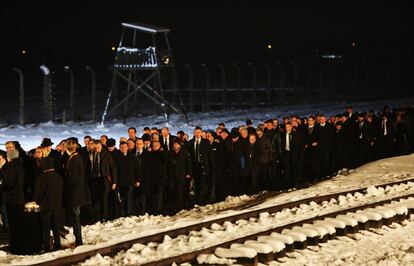 Asistentes a la ceremonia del 70 aniversario de la liberaci&oacute;n de Auschwitz caminan sobre la nieve para depositar sus velas en el memorial de Birkenau