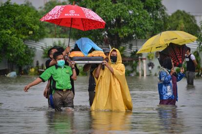 Personal médico traslada a una mujer de una zona inundada por las fuertes lluvias caídas en Banda Aceh (Indonesia).