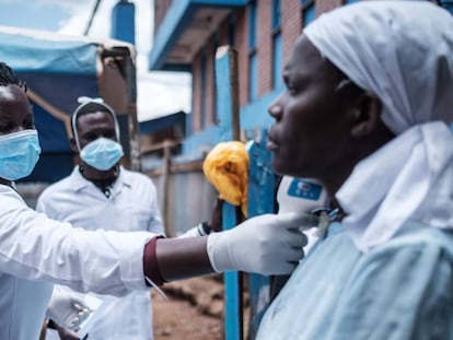 Tres trabajadores voluntarios toman la temperatura a una habitante del barrio de chabolas de Kibera, en Kenia.