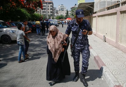 Un miembro de las fuerzas de seguridad palestinas ayuda a una anciana frente a la oficina de correos, en la ciudad de Gaza.