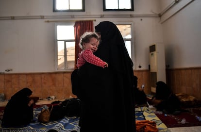 Una niña en brazos de su madre ríe mientras esperan en la frontera oeste de Raqa, Siria el 8 de octubre.