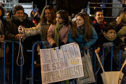 Dos niñas con un cartel dirigido al rey Melchor en la Cabalgata de los Reyes Magos en Madrid.