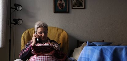 Una mujer teje mientras habla por teléfono en su casa.