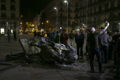 Un grupo de personas contempla la estatua de Franco derribada.