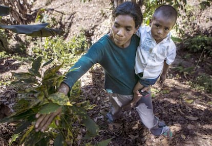 Uma mulher e seu filho com uma planta atingida.