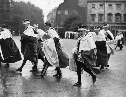 Un grupo de asistentes a la coronación se apresura bajo la lluvia desde la Abadía de Westminster después del acto.